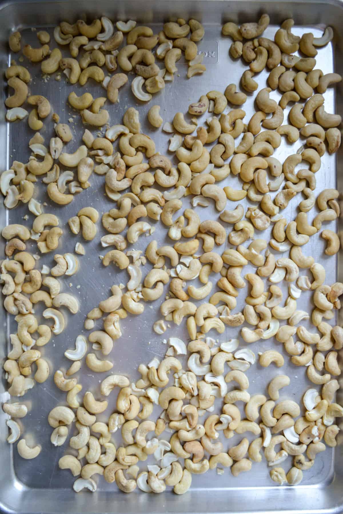Raw cashews on a baking sheet.