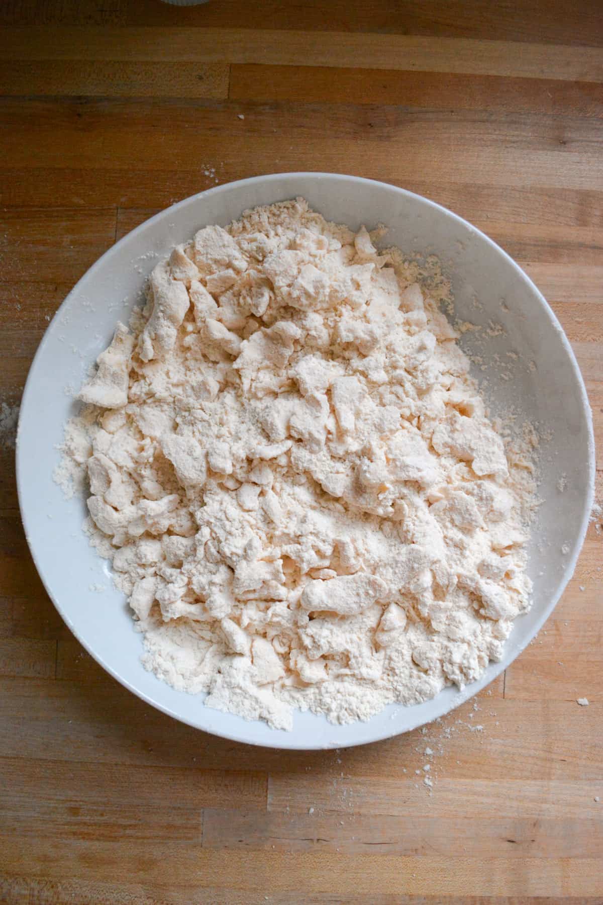 Vegan butter cut into flour in a wide shallow bowl.