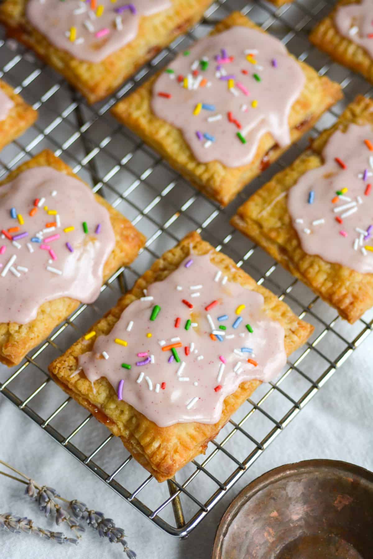 Homemade Vegan Strawberry Pop Tarts with glaze and sprinkles on top on a wire cooling rack.