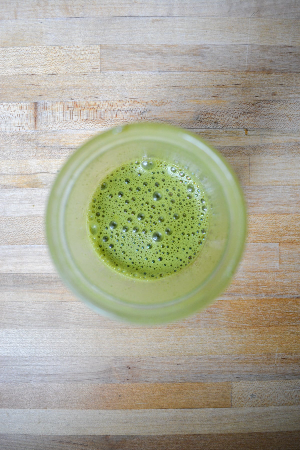 Matcha powder mixed with hot water in a glass jar.