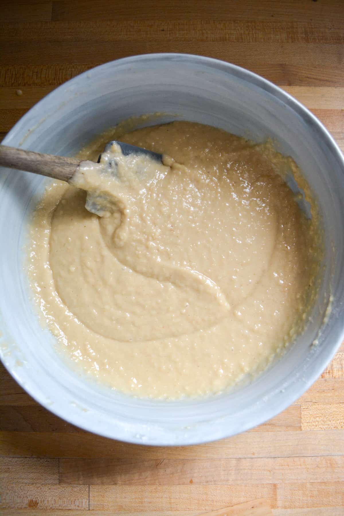 Vegan muffin batter in a bowl with a spatula on the upper left corner. 