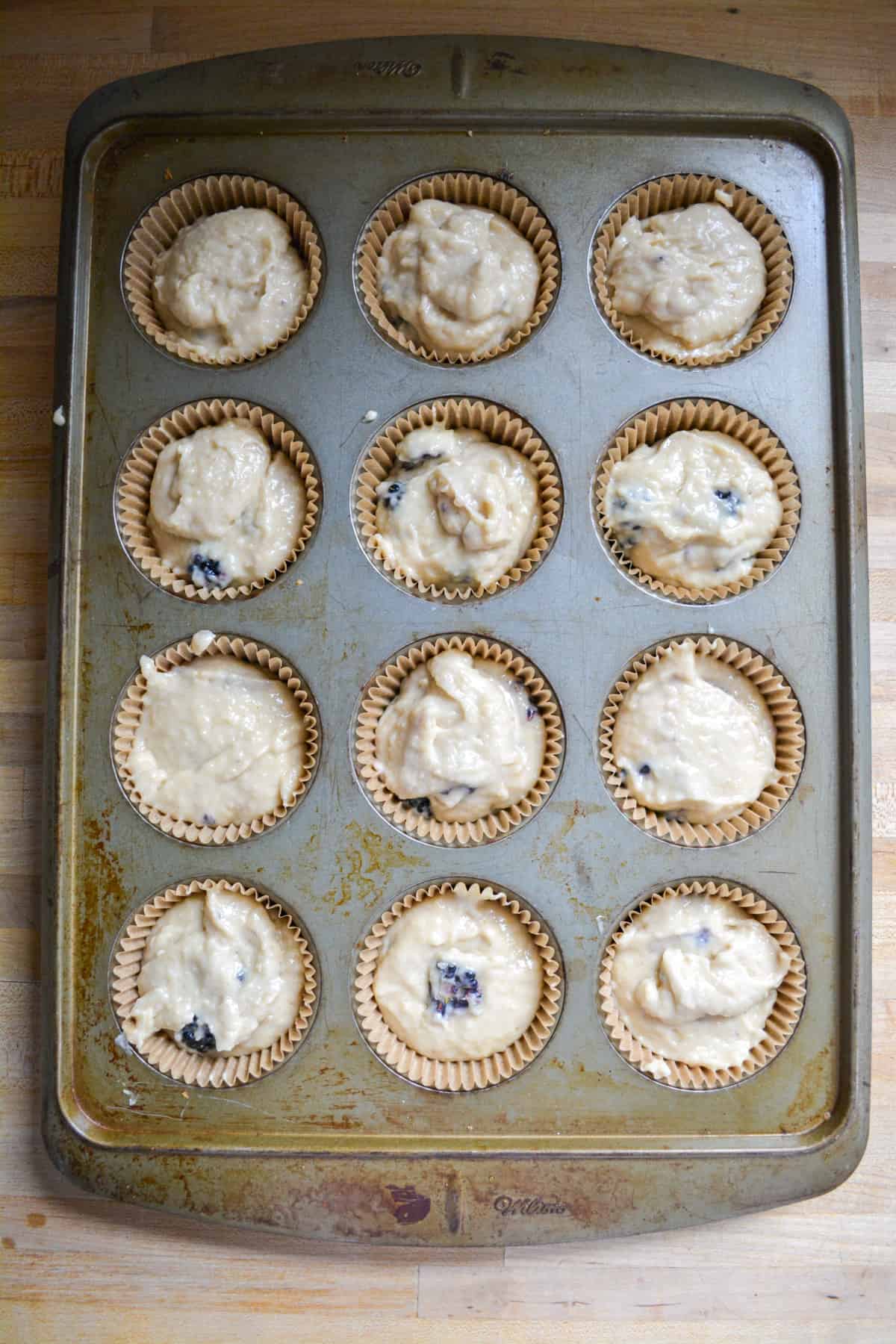 Vegan Blackberry muffin batter scooped into a lined muffin tin.