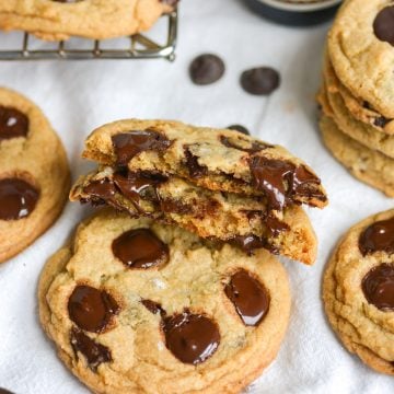 A broken in half vegan chocolate chip cookie leaning on another cookie.
