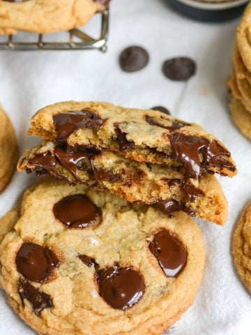 A broken in half vegan chocolate chip cookie leaning on another cookie.