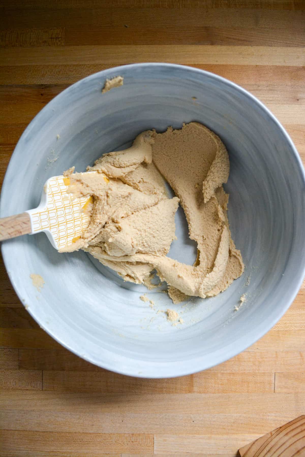 Vegan butter and brown sugar creamed together in a mixing bowl with a rubber spatula in the bowl.