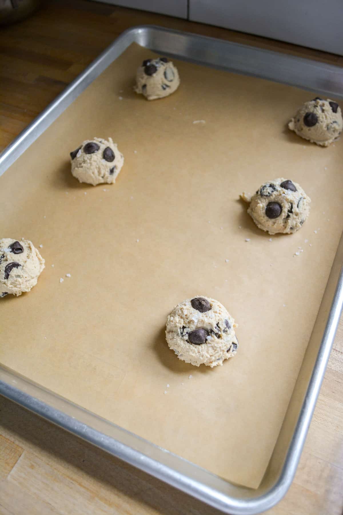 Cookie dough balls scooped onto a parchment-lined baking sheet.