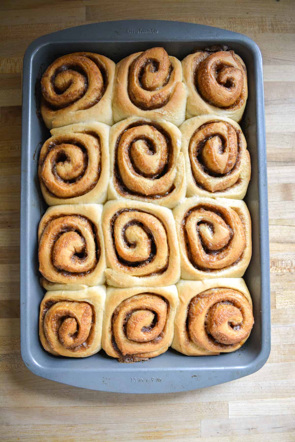 Baked cinnamon rolls in a 9 by 13 baking pan.