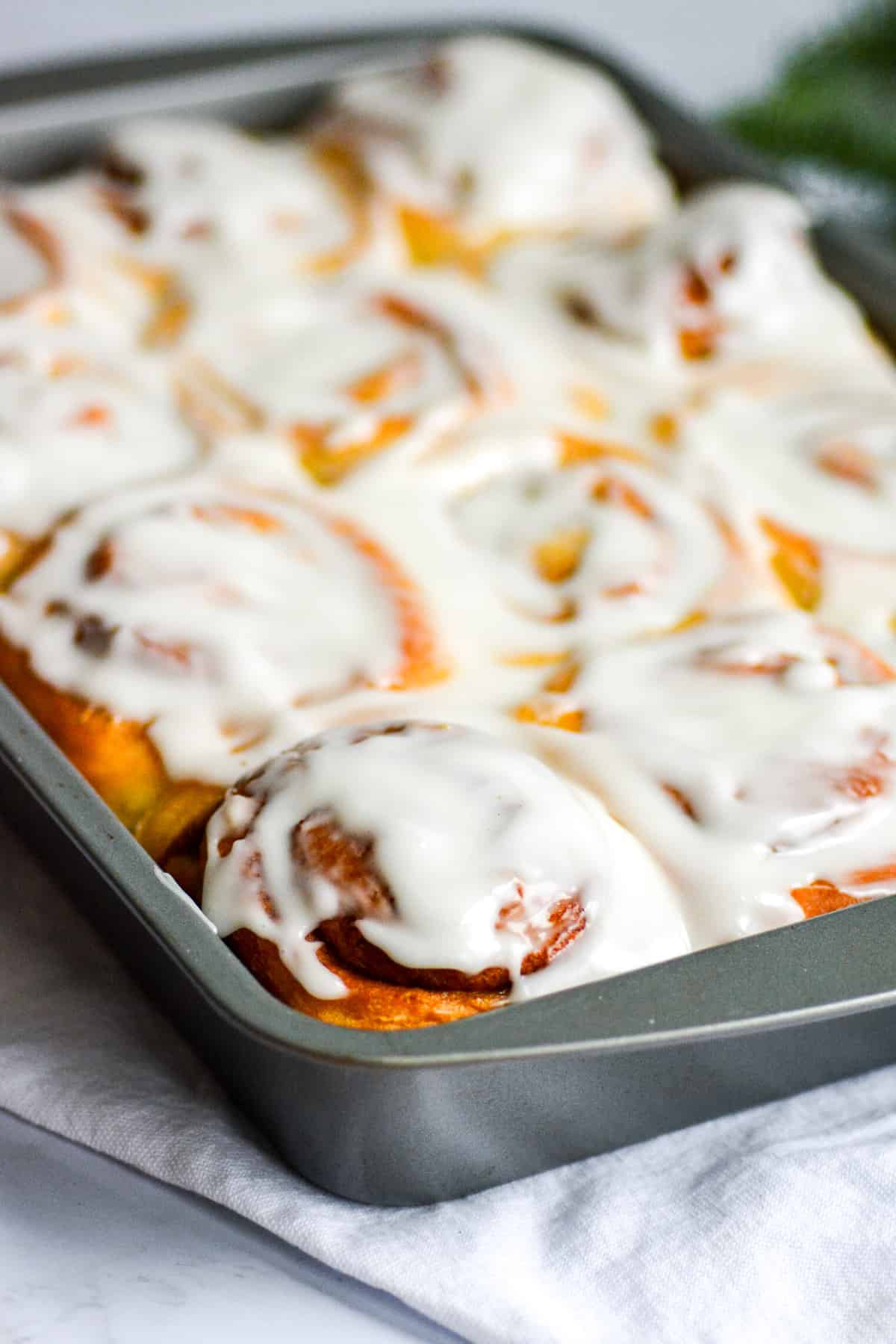 Vegan Cinnamon Rolls frosted with cream cheese frosting in a 9 by 13 pan.