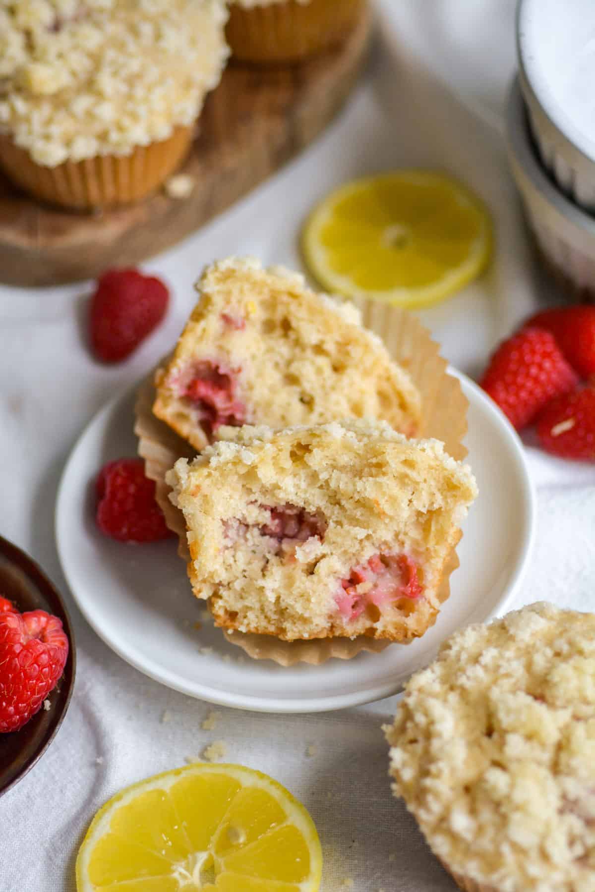 A Vegan Raspberry Lemon Muffin torn in half to show the interior of the muffin on a small plate.