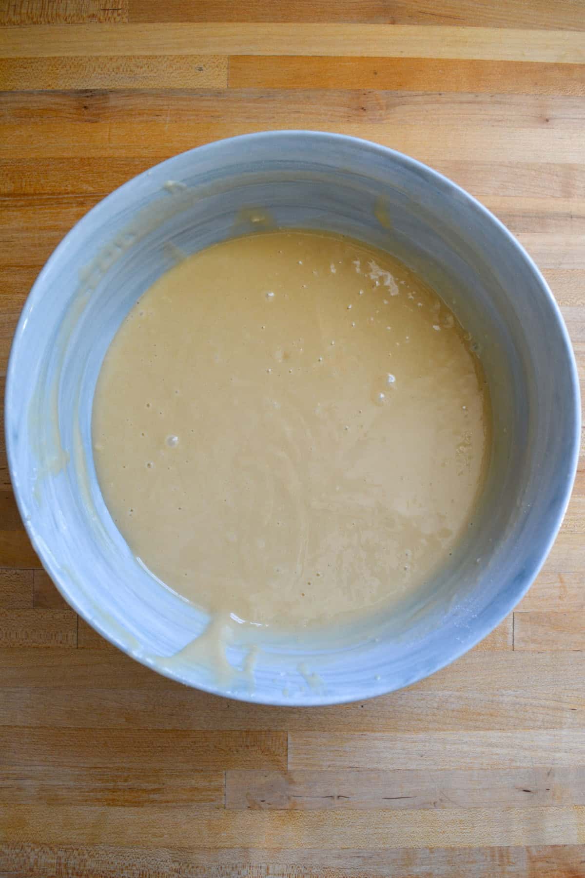 Vegan cake batter in a bowl on a wooden surface.