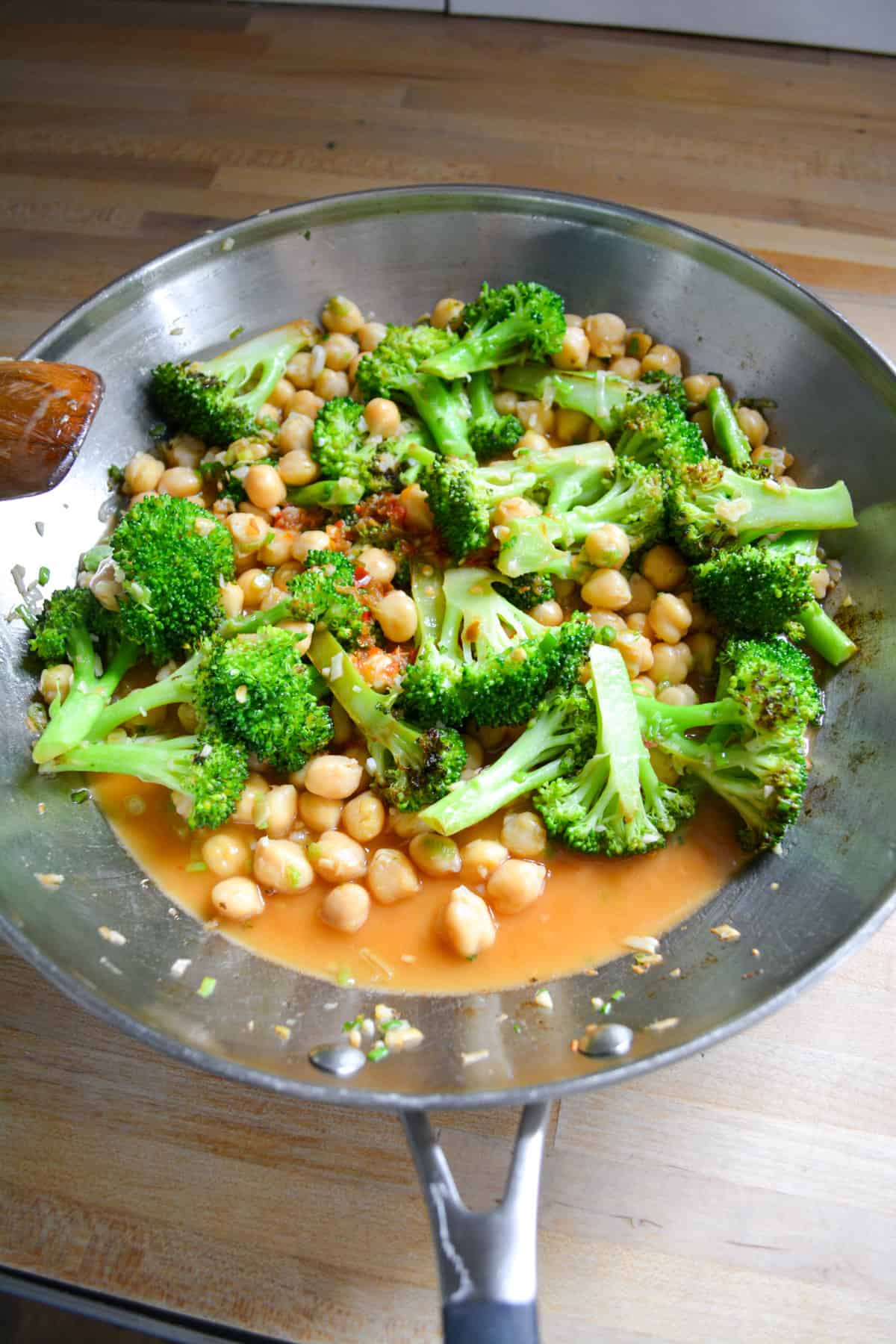 Chickpeas an stir fry sauce added to the skillet with the broccoli florets in it.