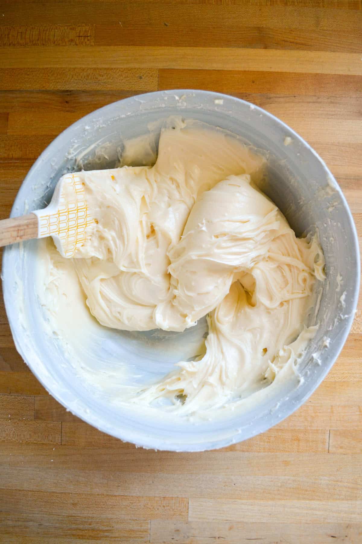 Chilled Vegan Cream Cheese Frosting in a mixing bowl with a rubber spatula to the left.