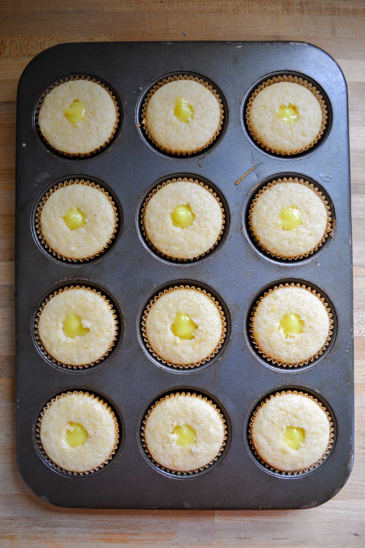 Vegan Lemon Cupcakes in a cupcake tin filled with lemon curd.