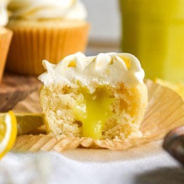 Vegan Lemon Curd Filled Cupcake cut in half to show the filling sitting on a cupcake liner.
