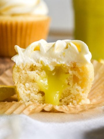 Vegan Lemon Curd Filled Cupcake cut in half to show the filling sitting on a cupcake liner.