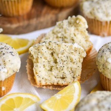Vegan Lemon Poppy Seed Muffin cut in half to show the inside with lemon slices in the foreground.