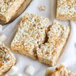 Vegan Rice Krispie Treat Square broken in half on a cloth with mini vegan marshmallows in the scene.