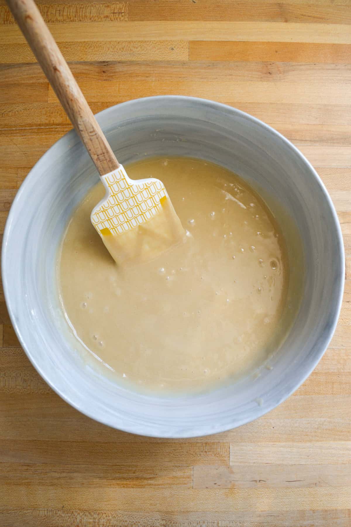 Vegan cupcake batter in a mixing bowl with a rubber spatula inside.