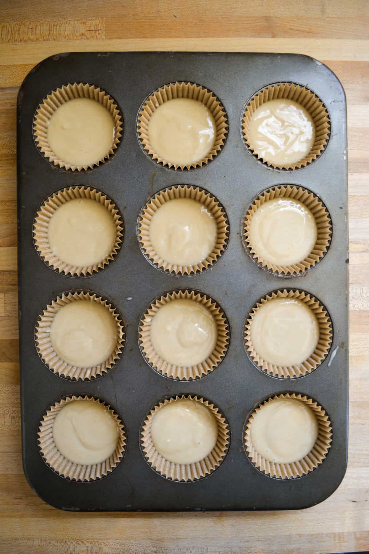 Cupcake batter is portioned into a lined cupcake tin.