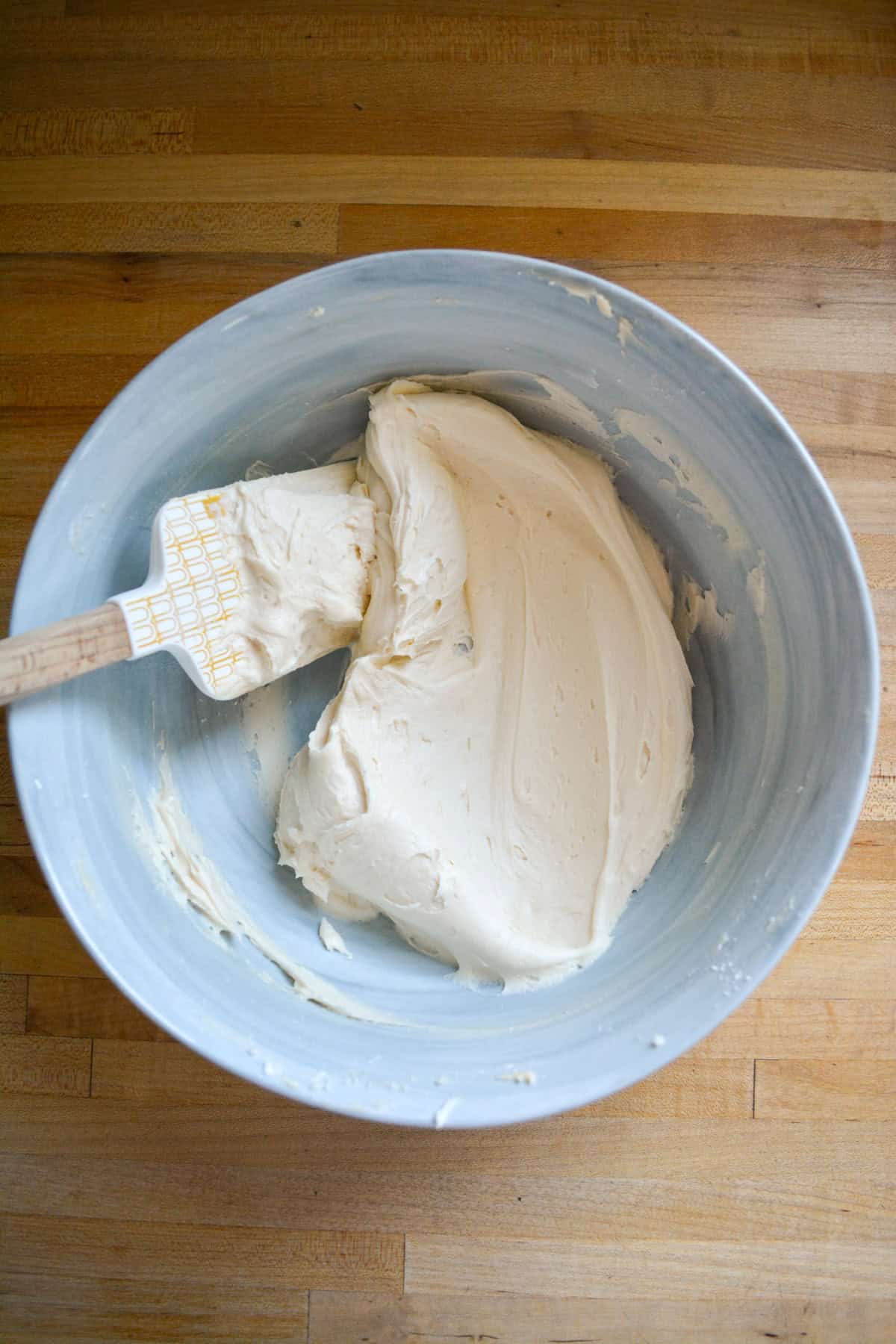 Vegan Vanilla Frosting in a mixing bowl with a rubber spatula in the bowl.