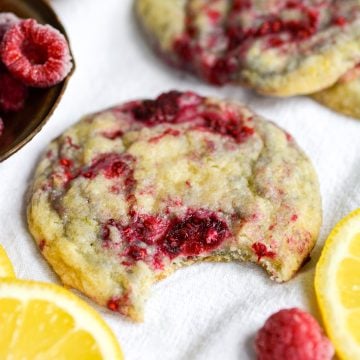 Vegan Raspberry Lemon Cookie with a bite taken out of it on a white cloth.