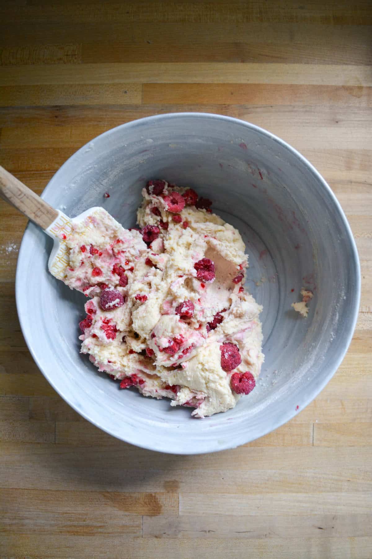 Frozen raspberries folded into the cookie dough in a large mixing bowl.