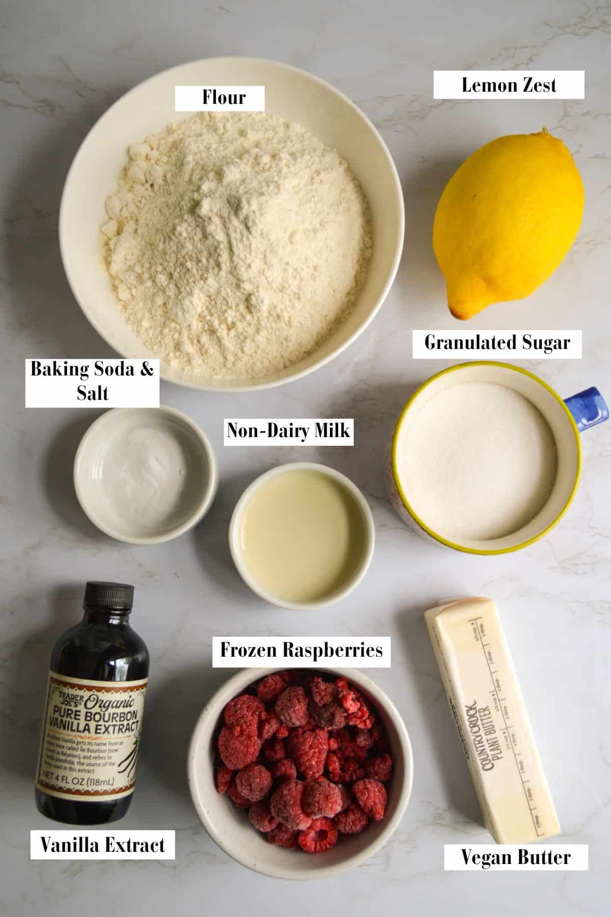 Ingredients for making Vegan Raspberry Lemon Cookies in small cups on a marble board.