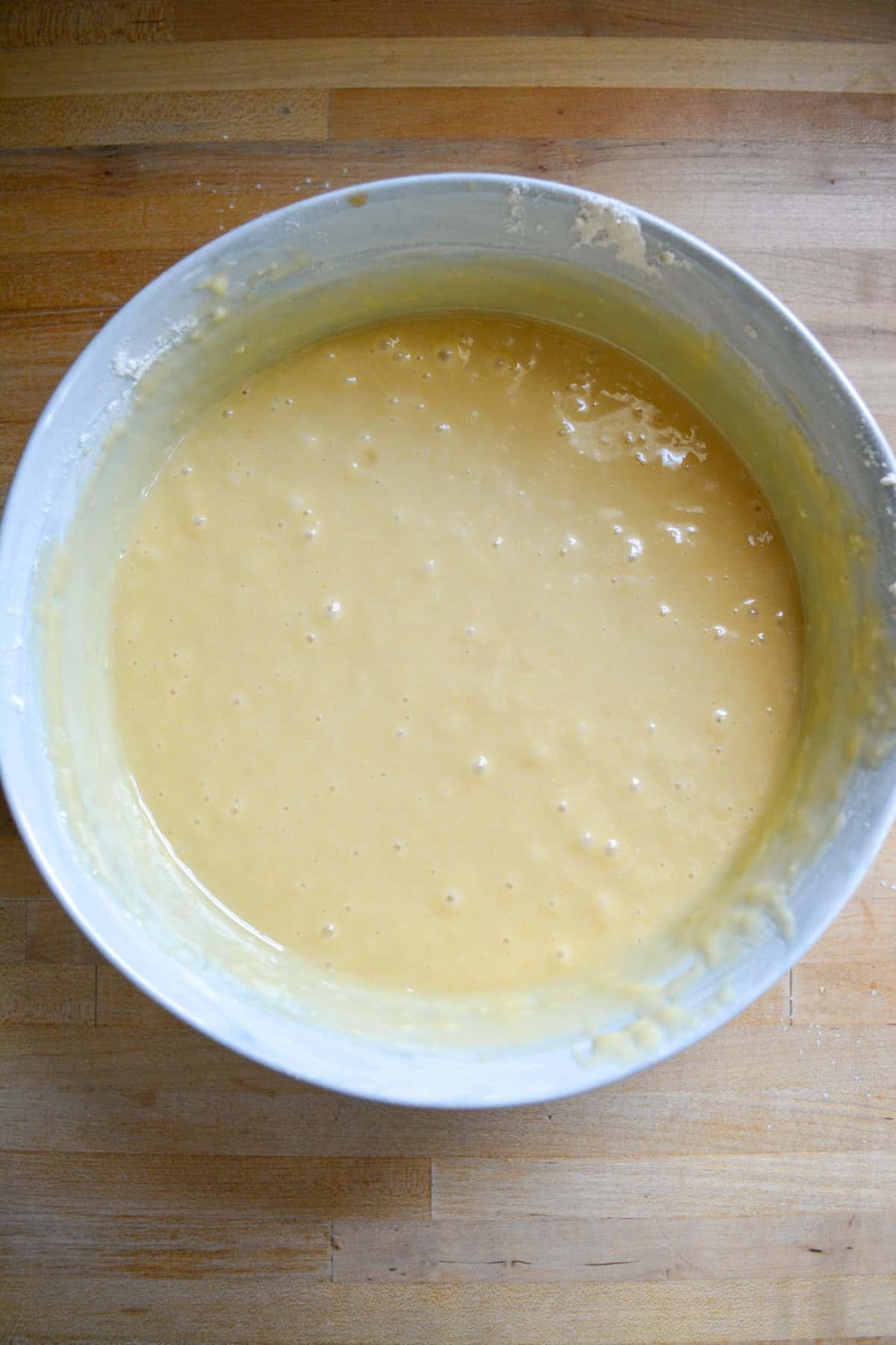 Vegan Yellow Cake batter in a mixing bowl on a wooden surface.