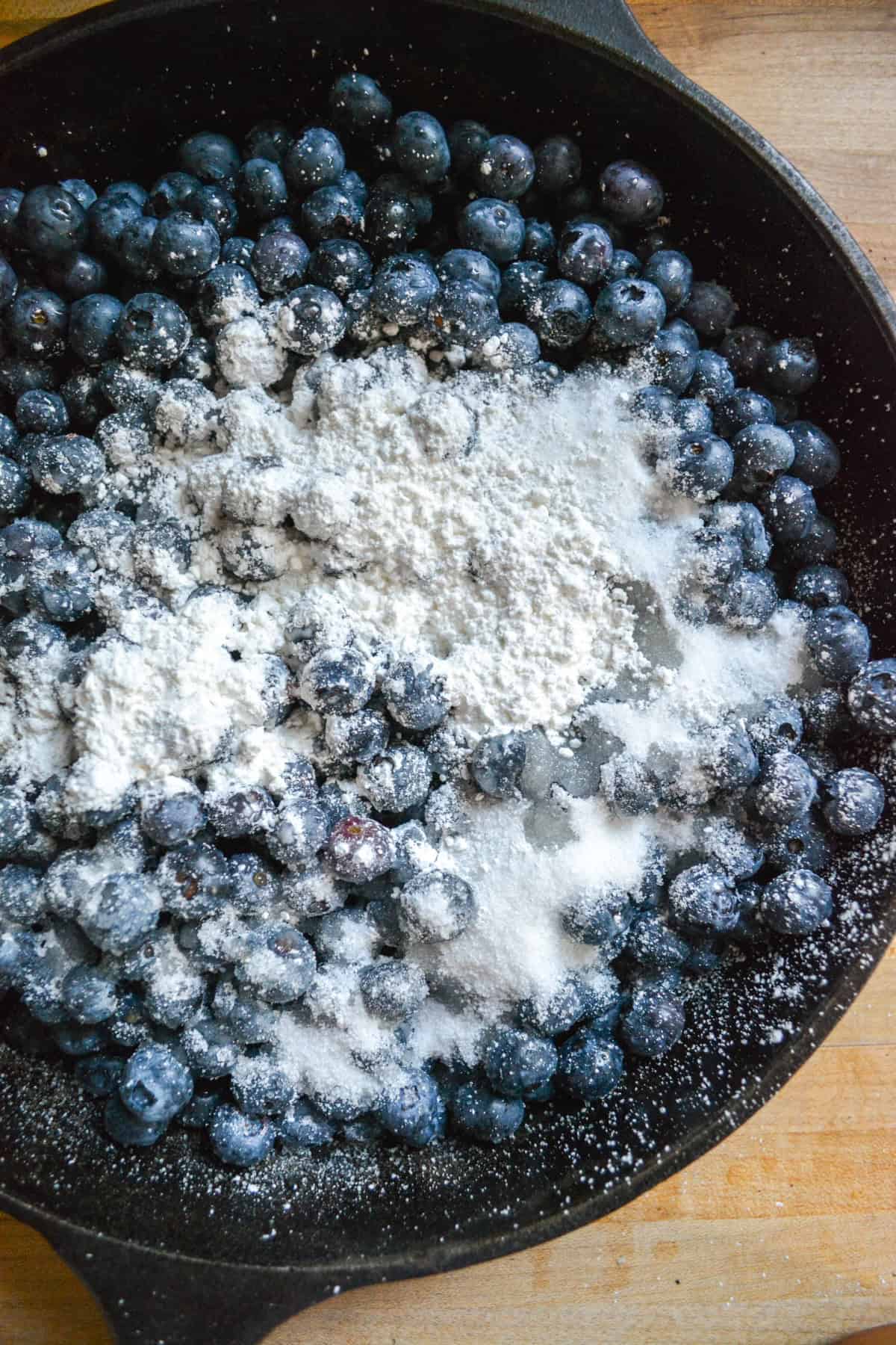 Blueberries, sugar and cornstarch in a cast iron skillet.