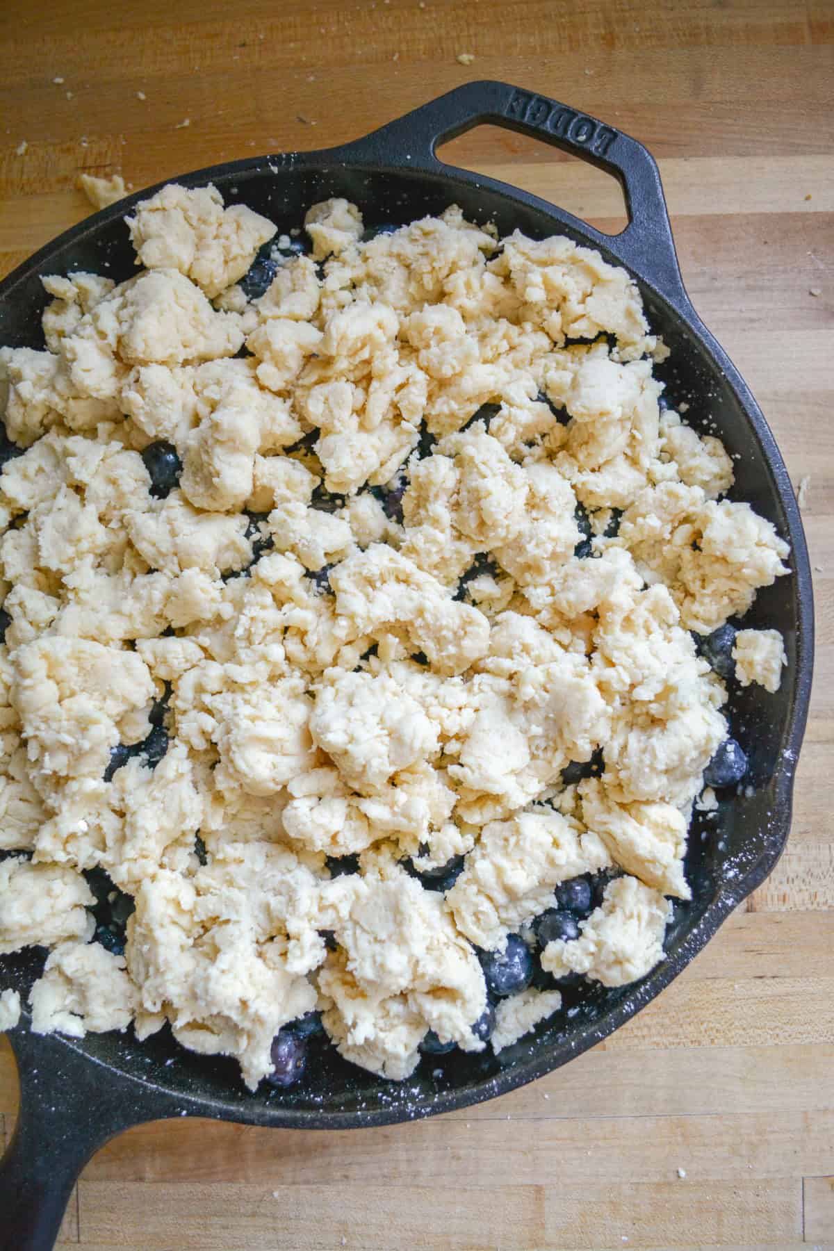 Biscuit topping scattered across the top of the blueberry mixture in a cast iron pan.