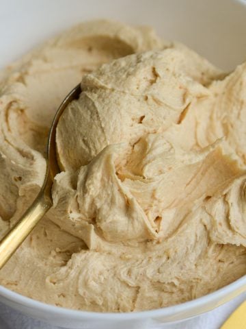 Vegan Peanut Butter Frosting in a bowl with a spoon inside the frosting,