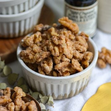 Vegan Candied Walnuts in a ramekin with more walnuts in the foreground.