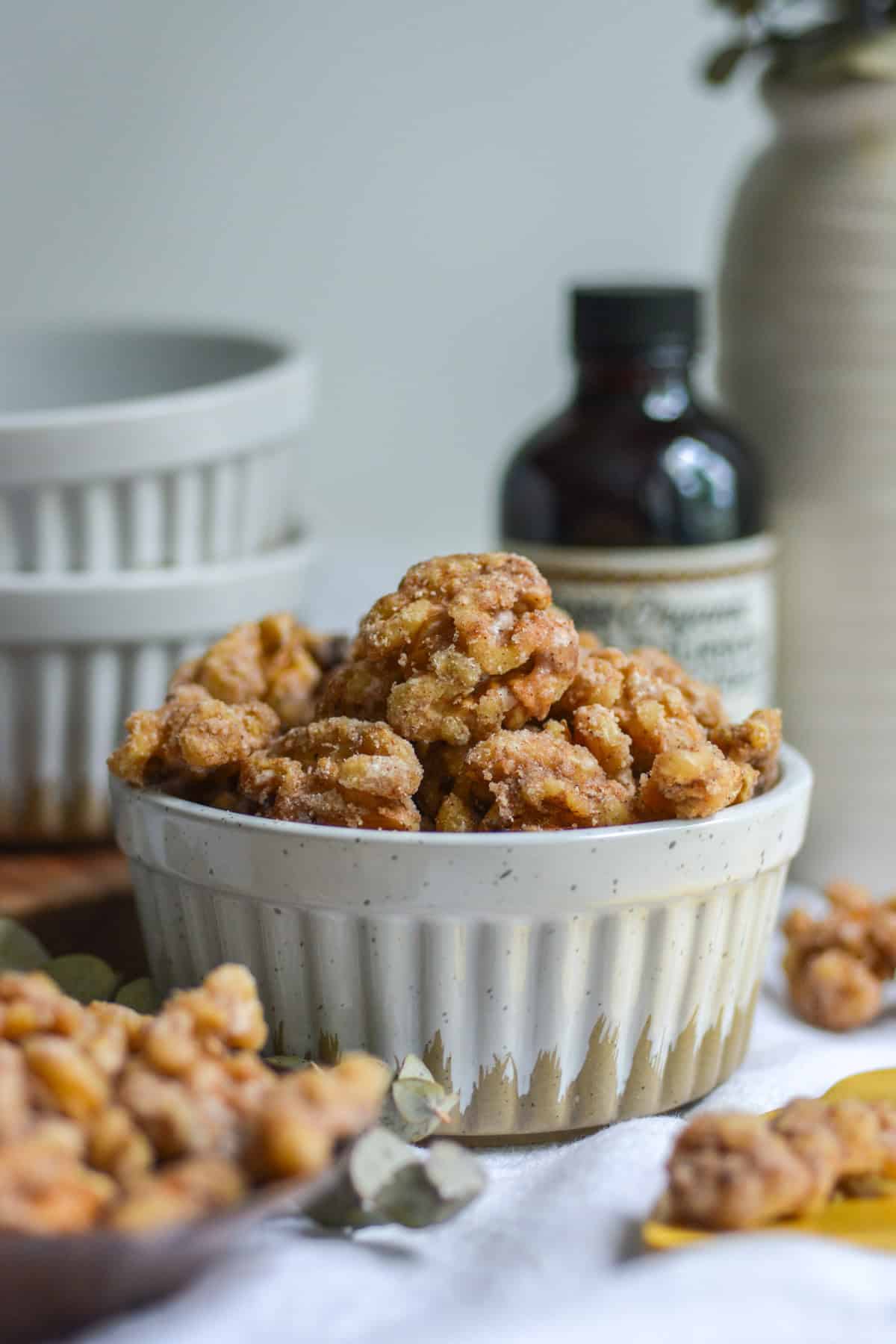 Vegan Candied Walnuts in a ramekin with more walnuts in the foreground.