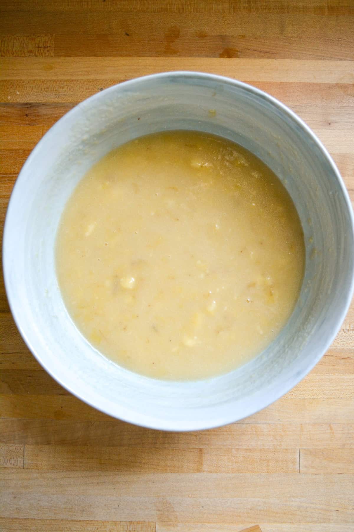 Wet ingredients in a large mixing bowl on a wooden surface.