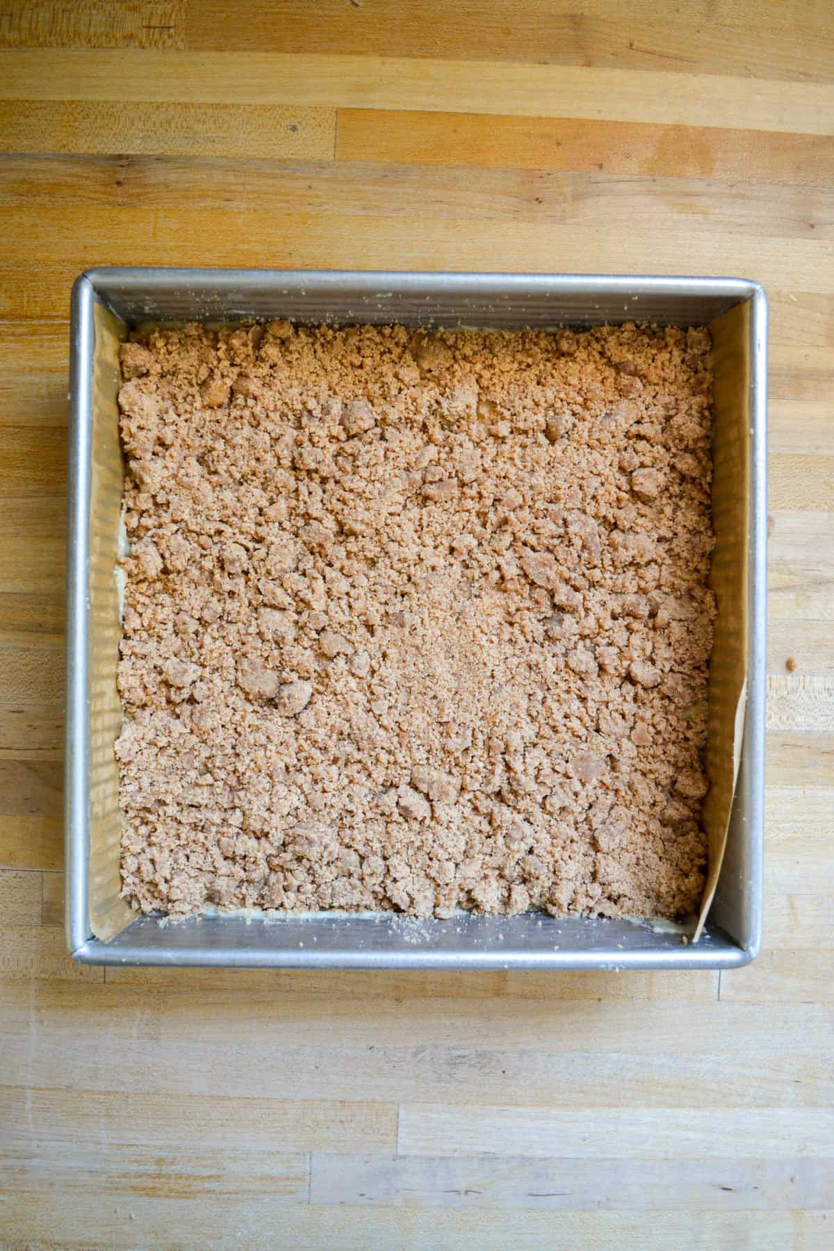 Cake batter topped with cinnamon streusel in a square baking pan.