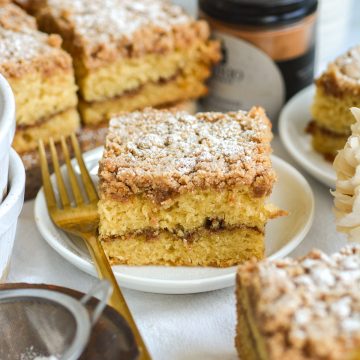 A slice of Vegan Coffee Cake topped with powdered sugar on a small plate.