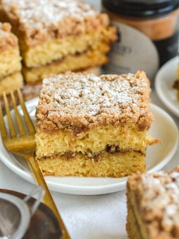 A slice of Vegan Coffee Cake topped with powdered sugar on a small plate.