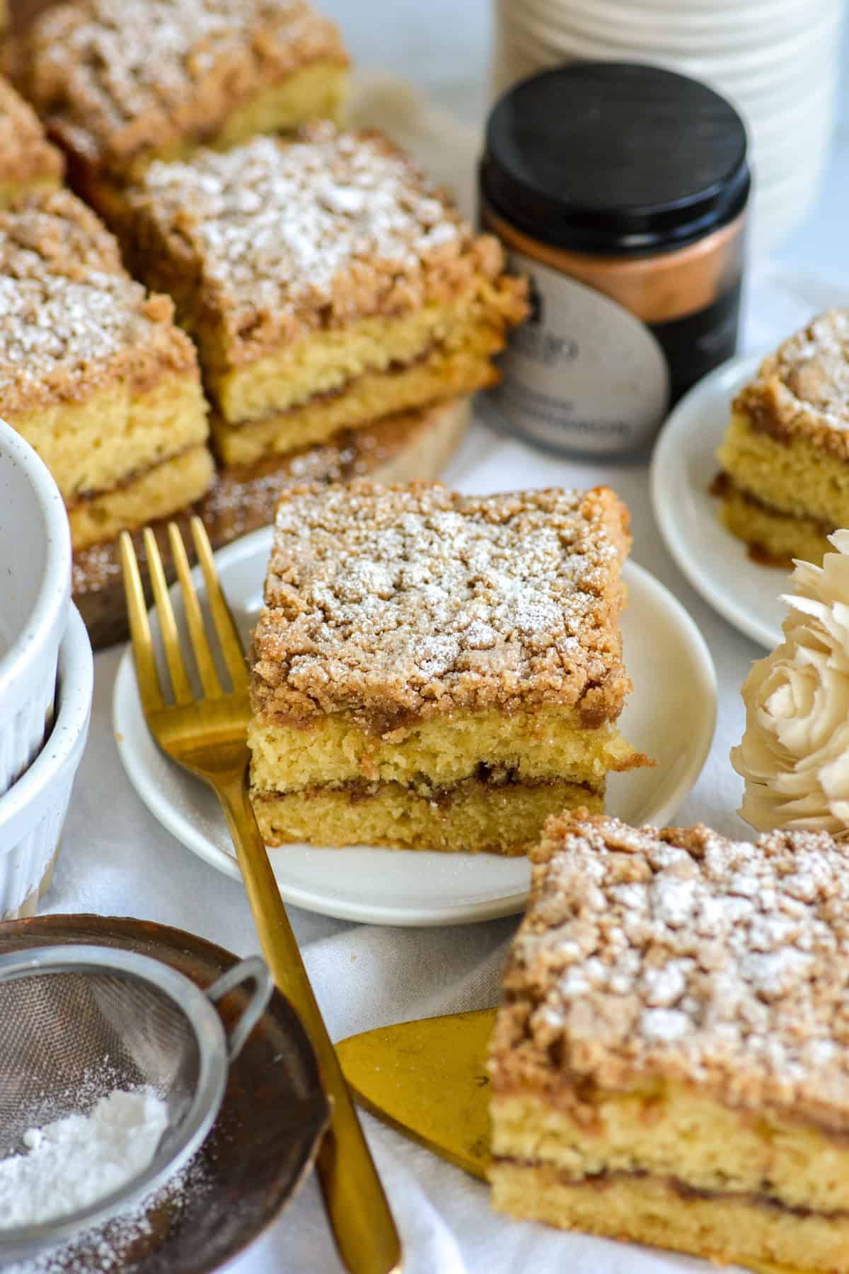 A slice of Vegan Coffee Cake topped with powdered sugar on a small white plate.