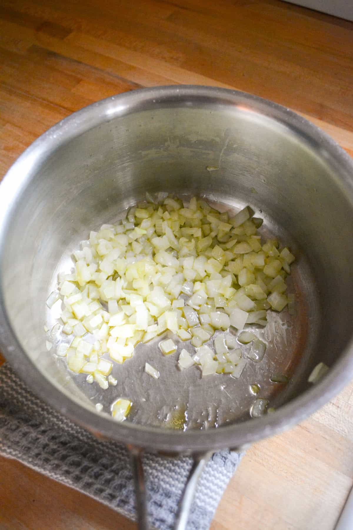 Onion sautéing in olive oil in a saucepan.