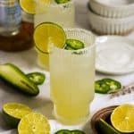 Skinny Spicy Margarita in a salt-rimmed glass with limes in the foreground.