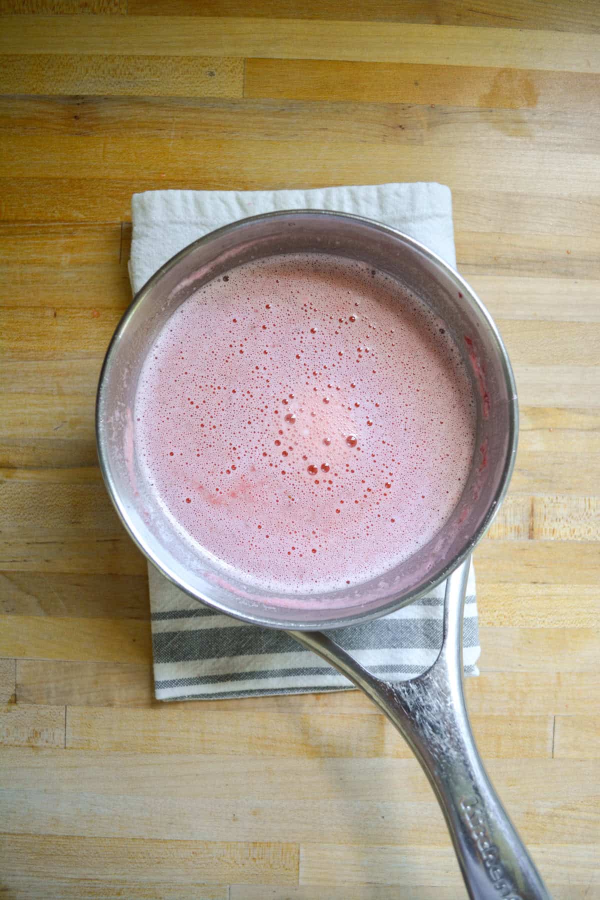 Strawberries blended into the mixture in a saucepan.