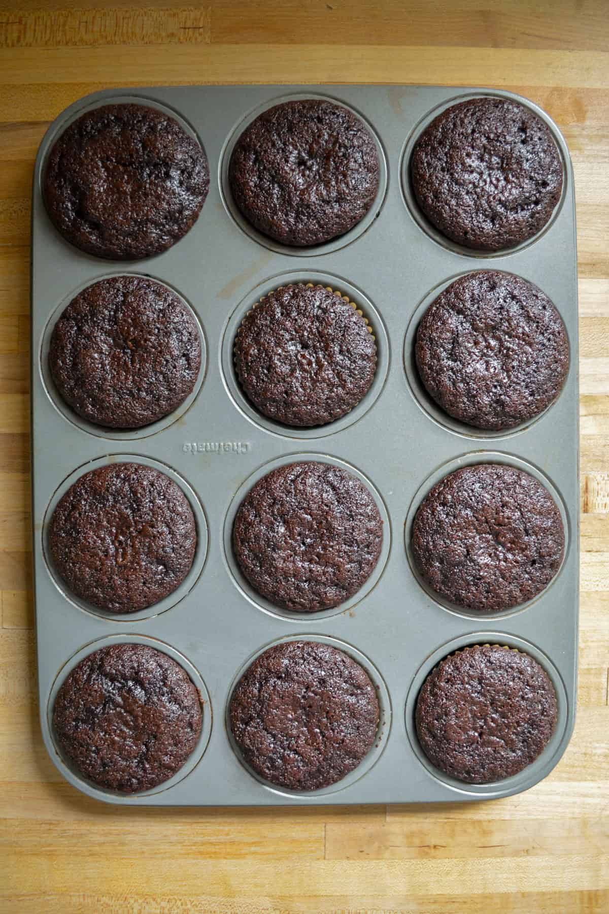 Baked chocolate cupcakes in a cupcake tin.