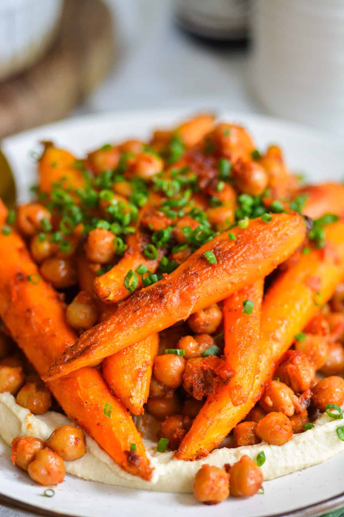 Roasted Harissa Carrots and Chickpeas on top of hummus on a plate.