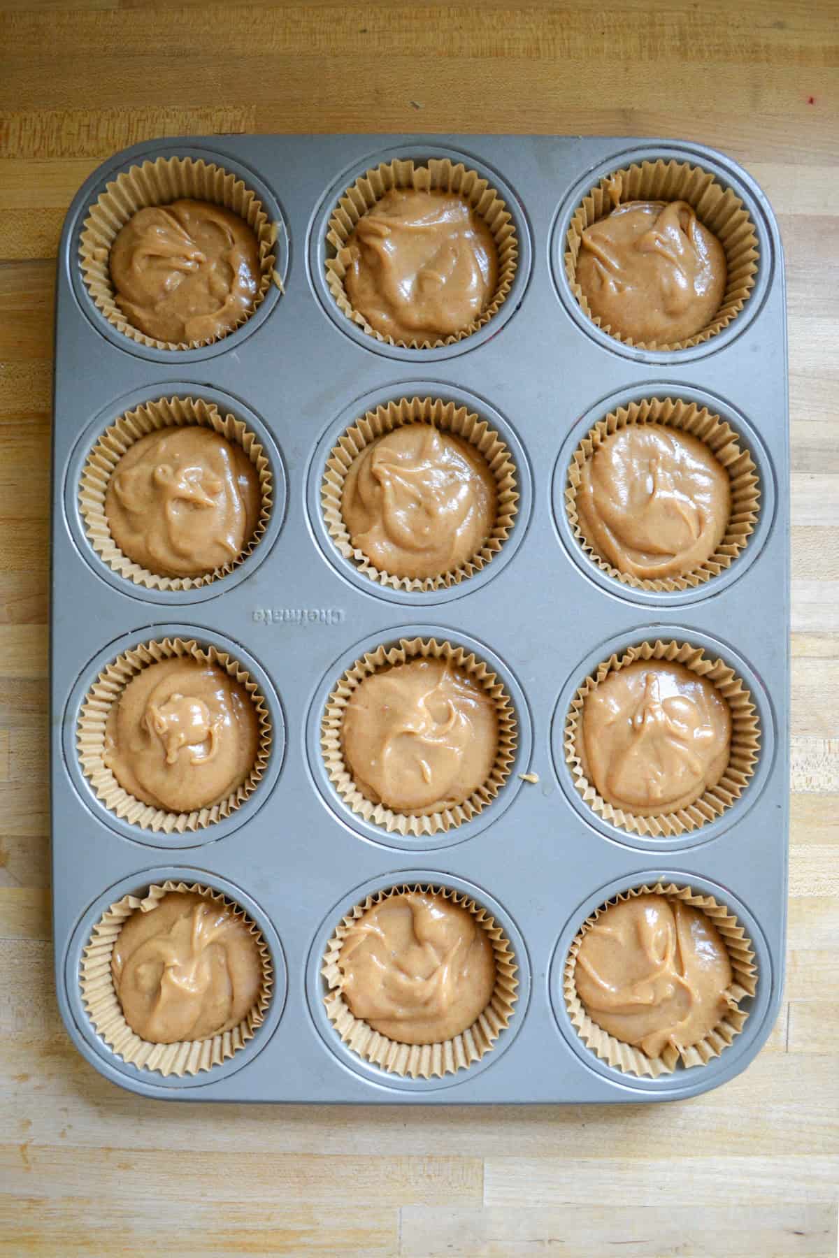 Cupcake batter scooped into a lined tin.