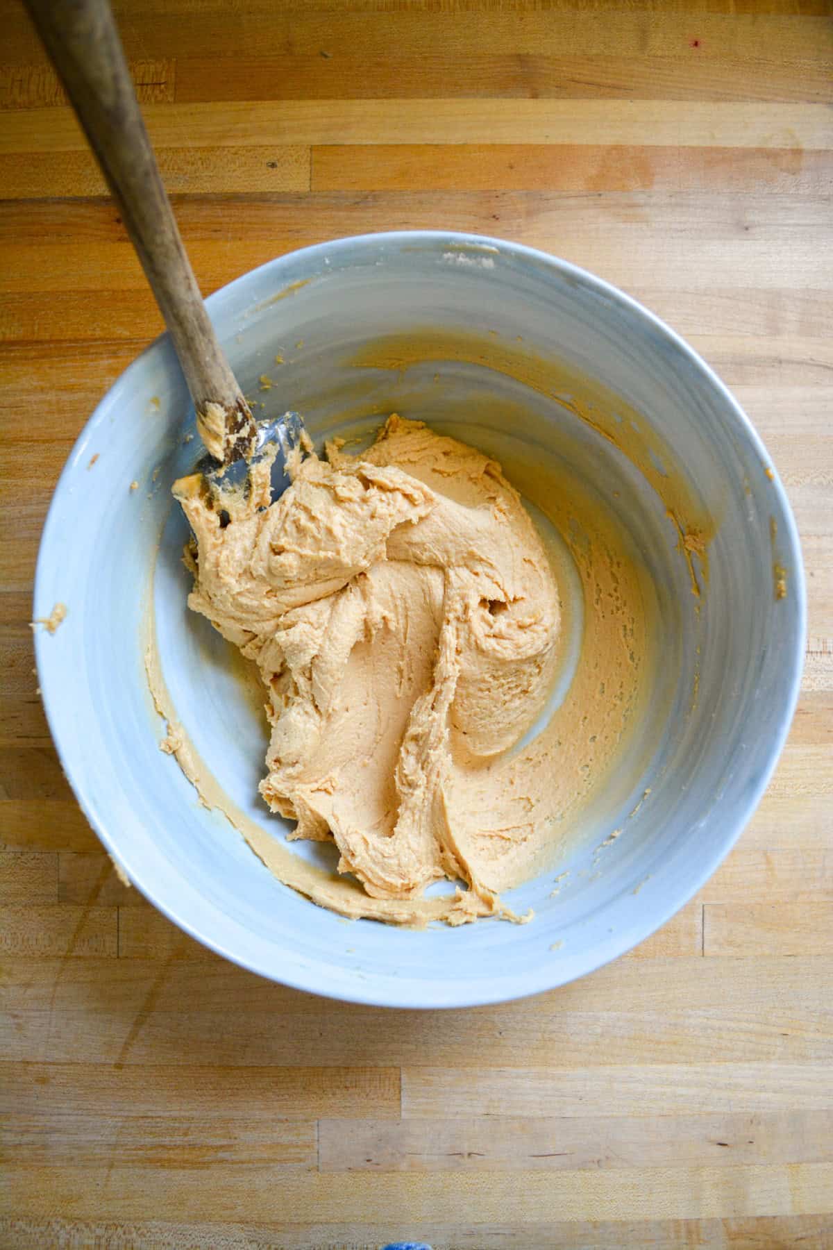 Biscoff frosting in a large bowl with a rubber spatula in it.