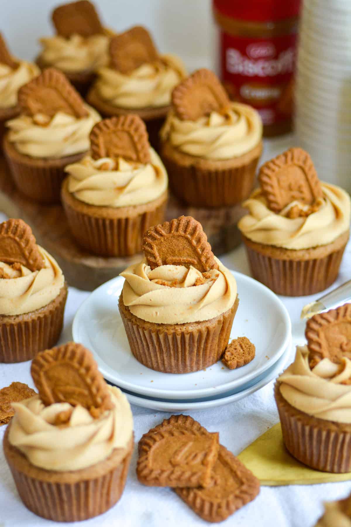 Vegan Biscoff cupcakes topped with frosting and Biscoff cookies on a linen cloth.