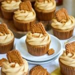 Biscoff Cupcake topped with a Biscoff cookie on a small plate with more cupcakes around the scene.