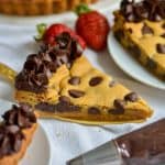 A slice of vegan chocolate chip cookie cake on a gold cake server.