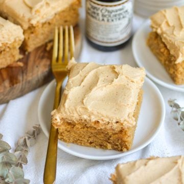 A slice of vegan peanut butter cake on a small plate next to a gold fork.