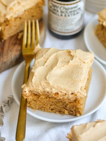 A slice of vegan peanut butter cake on a small plate next to a gold fork.